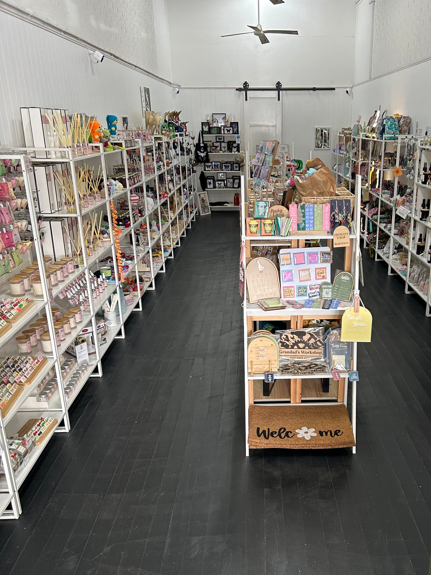 Store interior with shelves stocked with products and a central aisle.